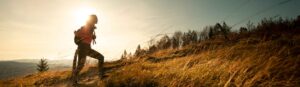 Hiker walking uphill in a field at sunrise